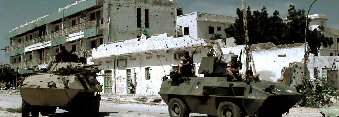 A US Marine Cadillac Gage Light Armored Reconnaissance Vehicle from the 3rd Light Armor Infantry Battalion (left) and Italian Soldiers in a Fiat-OTO Melara Type 6614 Armored Personnel Carrier (right) guard an intersection on the "Green Line" in Mogadishu.  The line divides the northern and southern part of the city and warring clans.  This mission is in direct support of Operation Restore Hope.